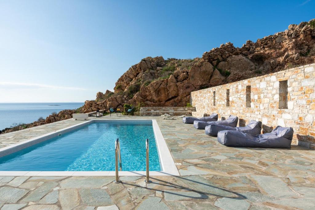 a swimming pool with pillows next to the ocean at Mont' Rock villas 2 in Posidhonía