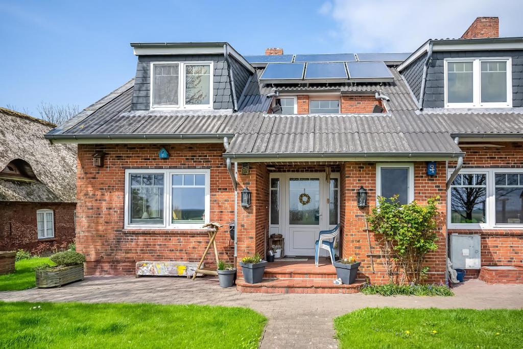 a brick house with a gray roof at Wohnung Hallighof in Honkenswarft