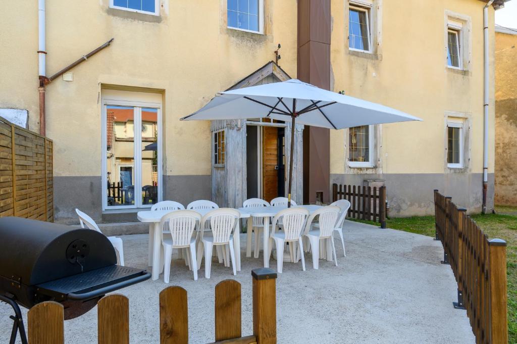 a table with white chairs and an umbrella at Gîte Les 3 Cerfs - 3 étoiles in Plainfaing