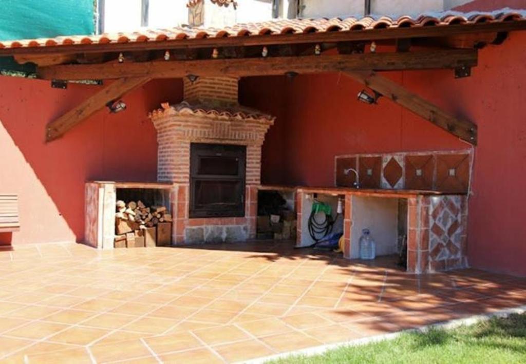 an outdoor patio with a brick fireplace next to a red wall at El Mirador De Campumedra in Vadillo