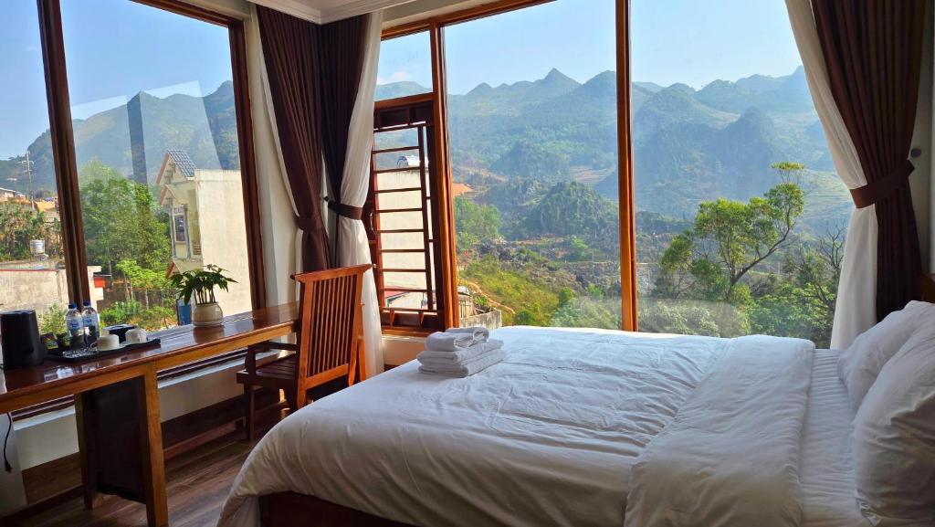 a bedroom with a bed and a desk with a large window at Viet Son Lam Hotel in Dồng Văn