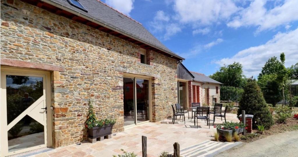a stone house with a patio and dining area at Ô Pré des Fleurs in Amanlis