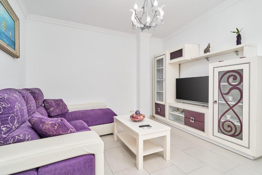 a living room with a purple couch and a tv at Apartamento Lola 2 in Nerja