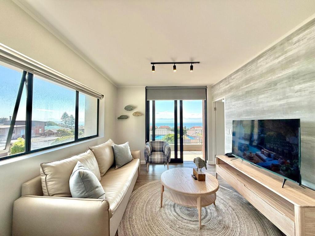 a living room with a couch and a large tv at Indigo Tide - Mossel Cove Unit 201 in Mossel Bay