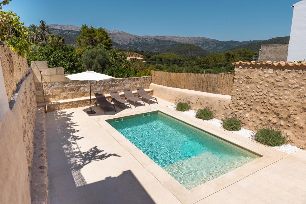 a swimming pool with chairs and an umbrella in a backyard at Cas Suis 9 in Campanet