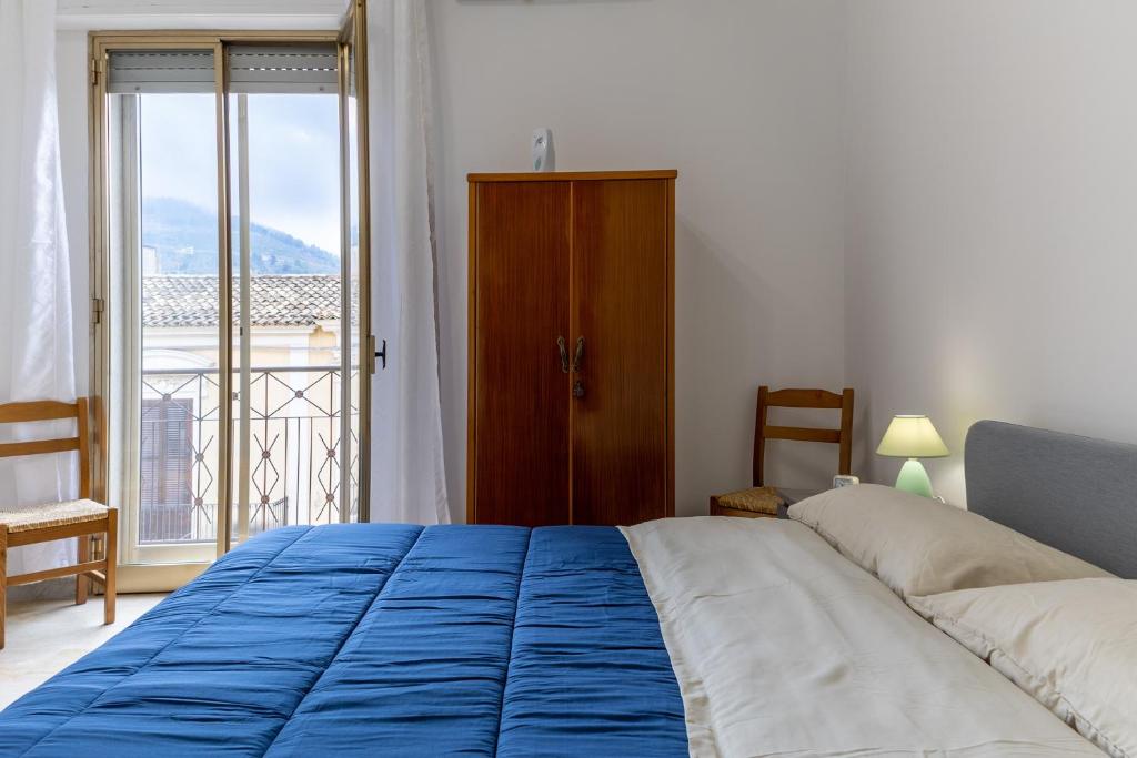 a bedroom with a large bed with a blue blanket at Pollicita 80 in Chiaramonte Gulfi