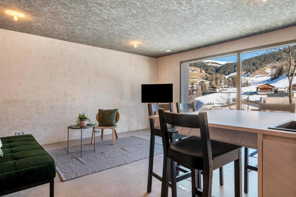a living room with a table and chairs and a window at Lena Dolomites Gartensuite in Villnoss