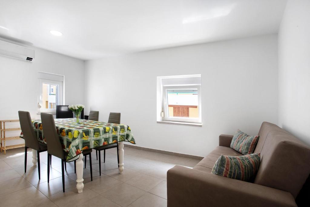 a dining room with a table and chairs and a couch at Casa Ribeiro Alojamento Local in São Martinho do Porto