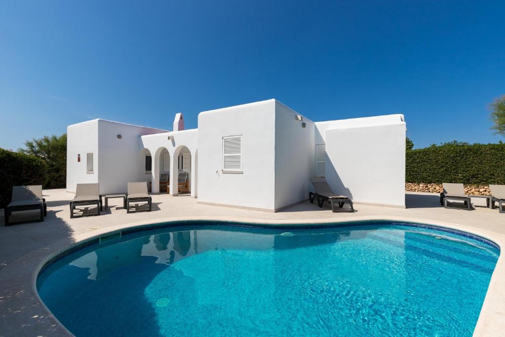 a villa with a swimming pool in front of a house at Ca Sa Mola in Cala Santandria