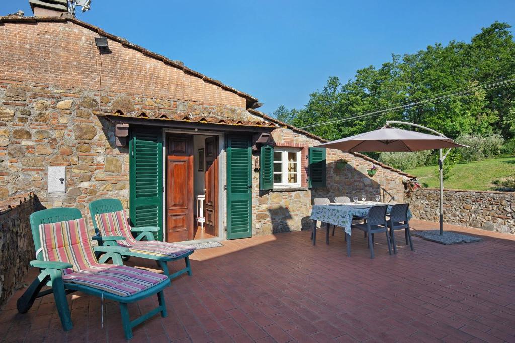 a patio with chairs and a table and an umbrella at Emma e Adele House in Marlia