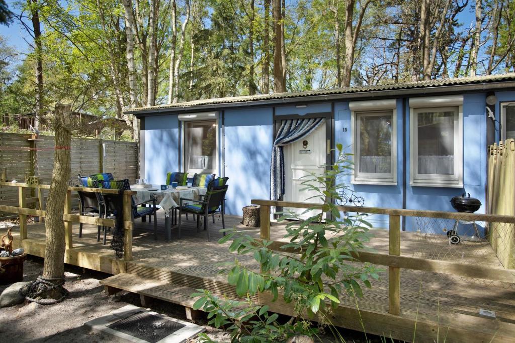 a blue house in the woods with a table and chairs at Bungalow Hörselberg, Bgl 15 in Dranske