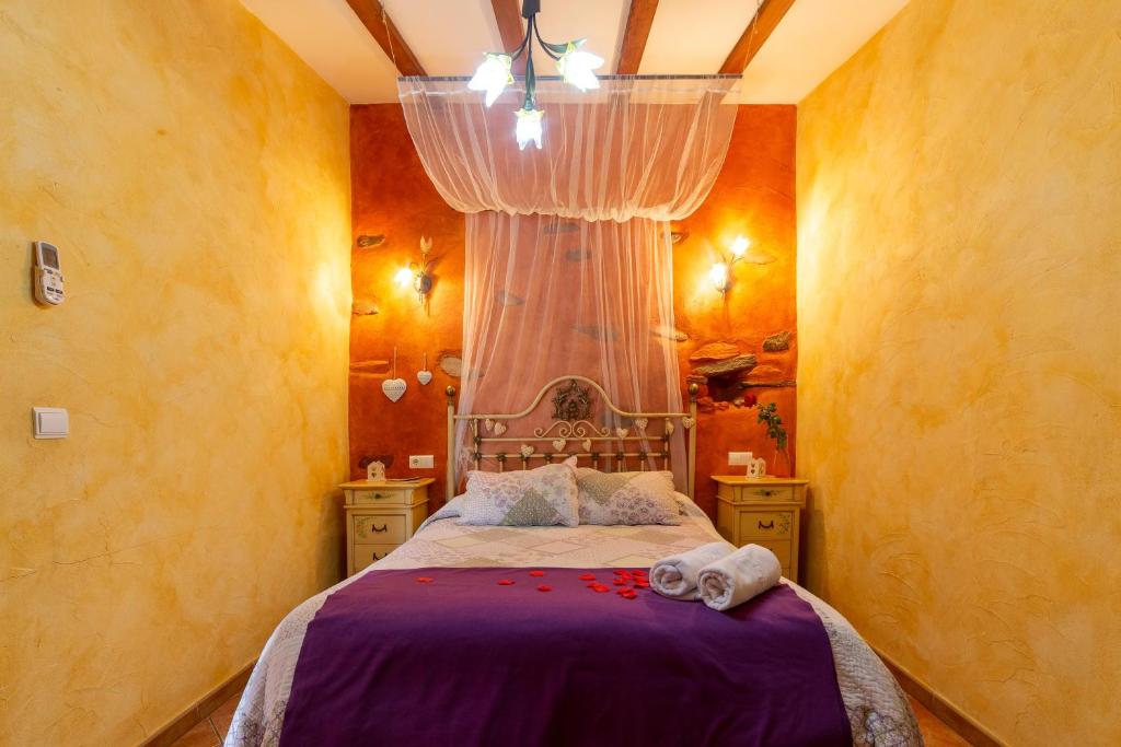 a bedroom with a bed with purple sheets and a window at Casa Rural Jaraiz Vip in Laroya