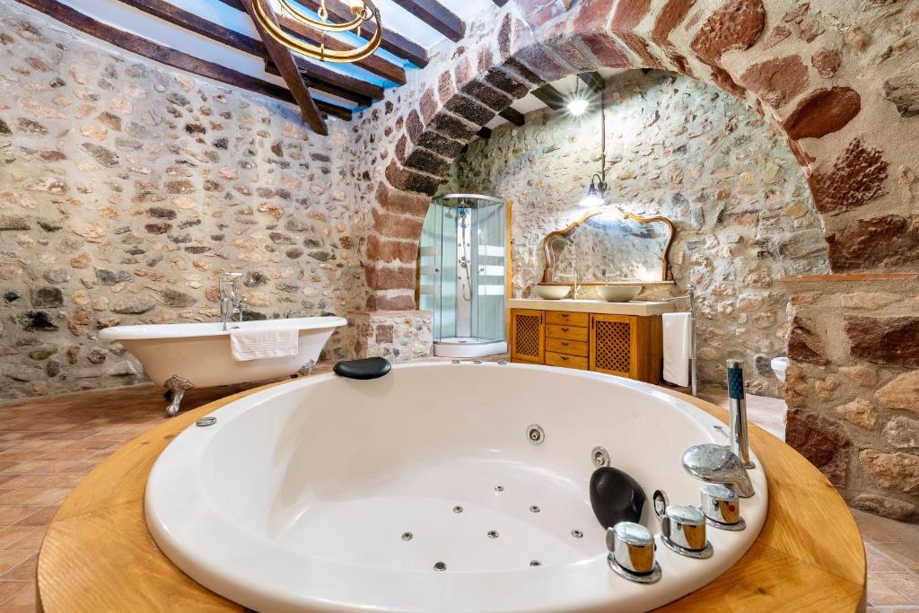 a large bath tub in a bathroom with a stone wall at Casa Encanto con Jacuzzi in Montroig
