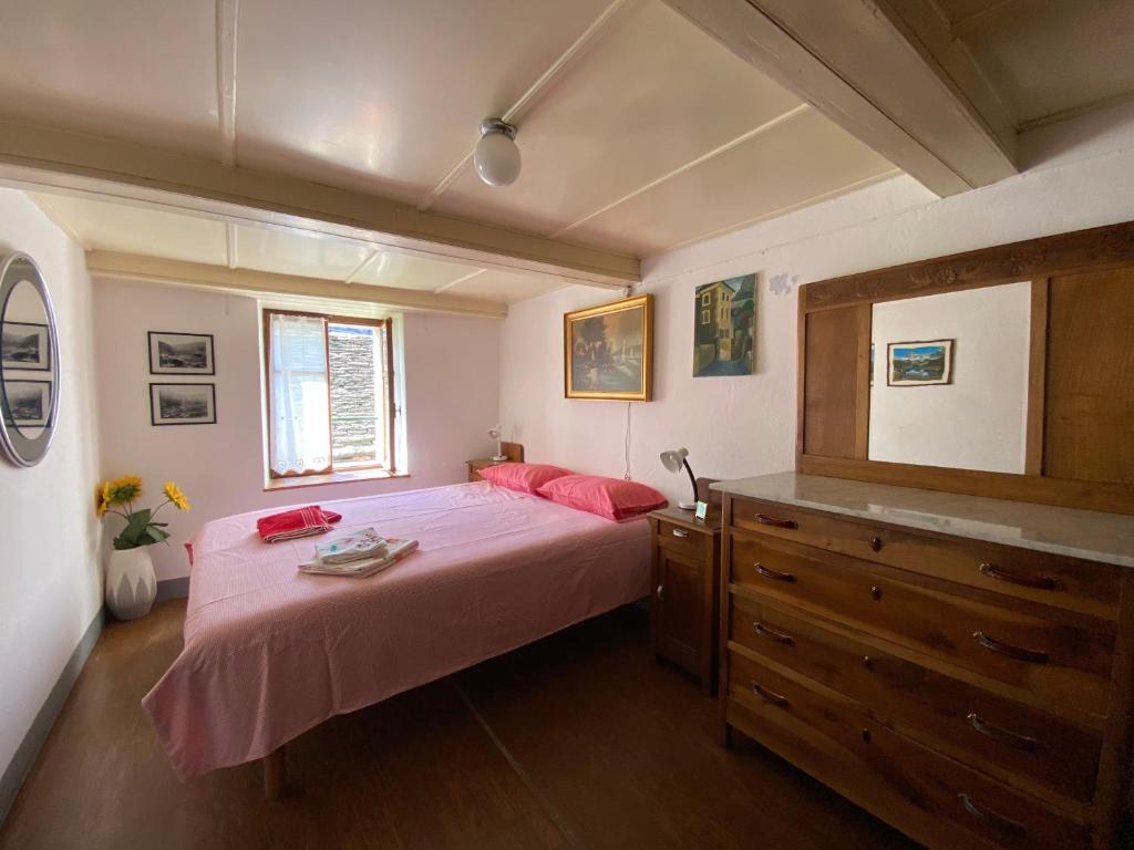 a bedroom with a bed with pink sheets and a dresser at La Casa di Sissy in Trasquera