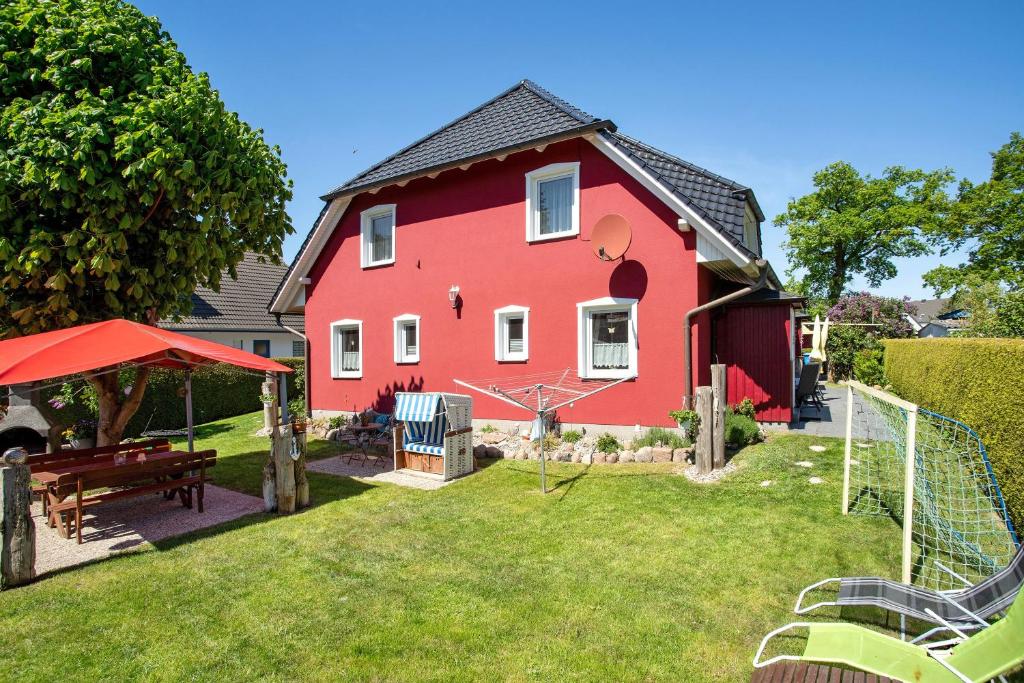 a red house with a picnic table in the yard at Fewo 14 - Halbinsel Darss - Ostsee in Wieck