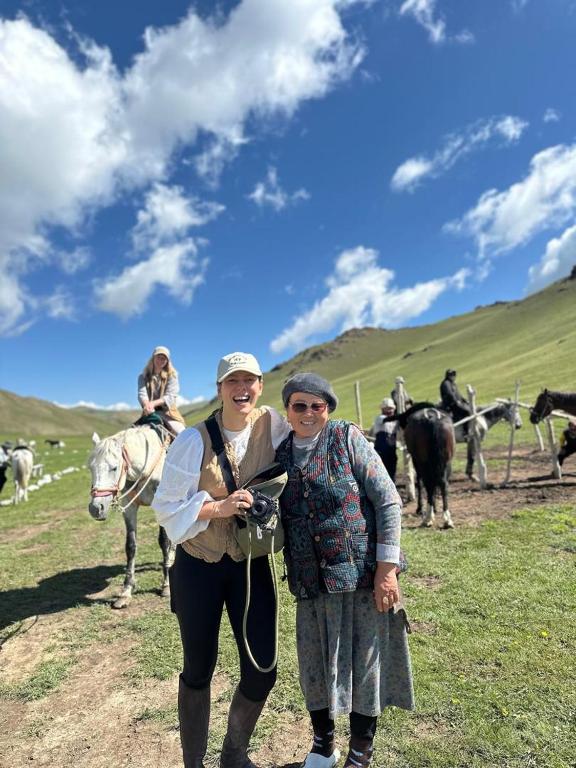 two women standing in a field with a herd of horses at Azamat Nomad Camp in Song-Kul