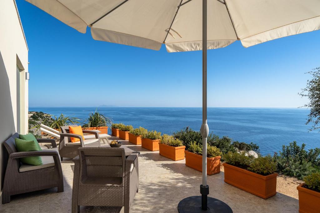 a patio with chairs and an umbrella and the ocean at Joy Breeze in Kefallonia