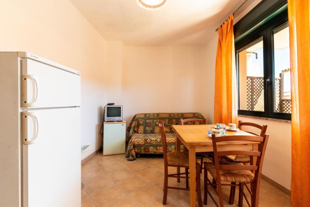 a dining room with a table and a refrigerator at Appartamenti Cavour cod C in Villasimius