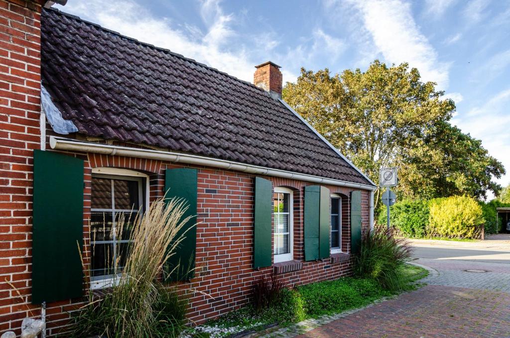 an old brick building with green shutters on a street at Ferienhaus Segelboot in Krummhörn
