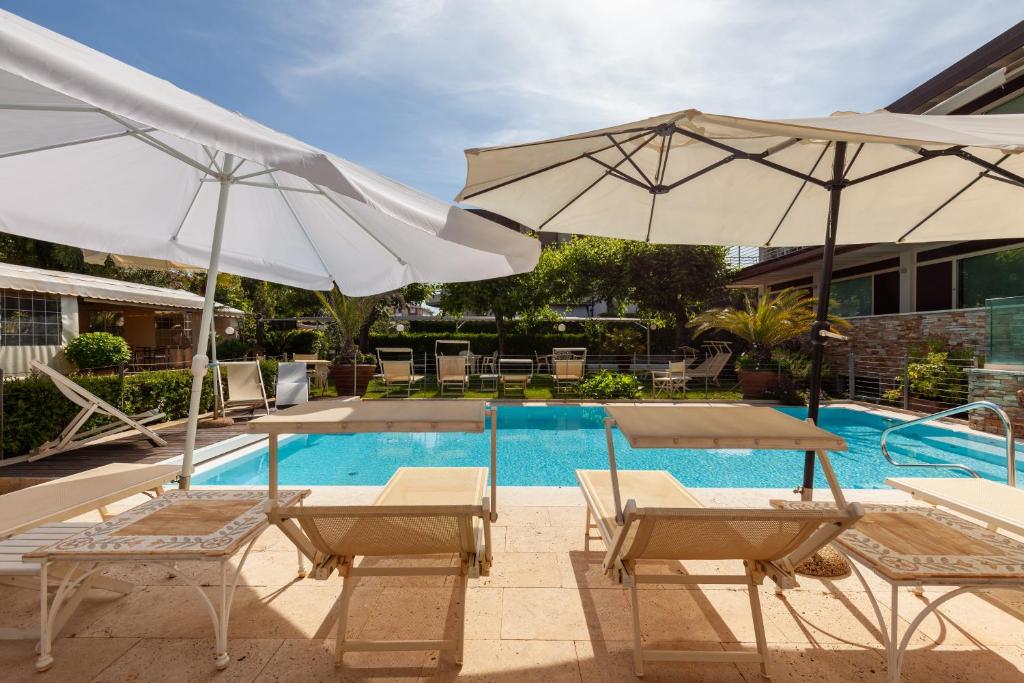 a pool with two chairs and two umbrellas at Appartamento Bacco in Lido di Camaiore