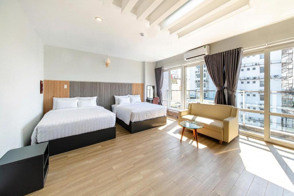 a hotel room with two beds and a couch at Hola Hotel in Can Tho