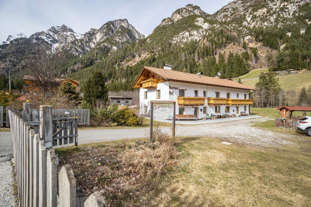a house with a fence in front of a mountain at Gartnerhof Apt Glücksklee in Colle Isarco