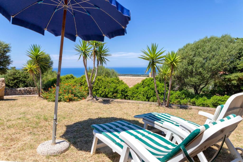 a couple of chairs and an umbrella with the ocean at Fantastico quadrilocale vista mare in Trinità d'Agultu e Vignola