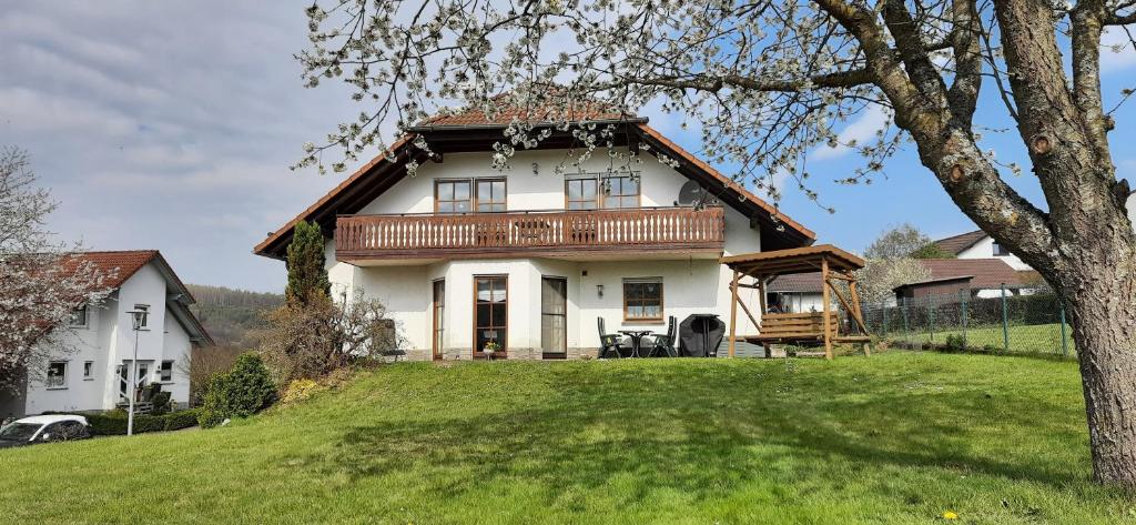 a house on a hill with a green yard at Ferienwohnung Nationalparkblick in Altenlotheim