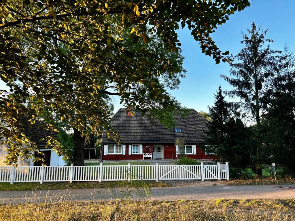 a white fence in front of a red house at Landhaus Schwerin in Kirch Jesar