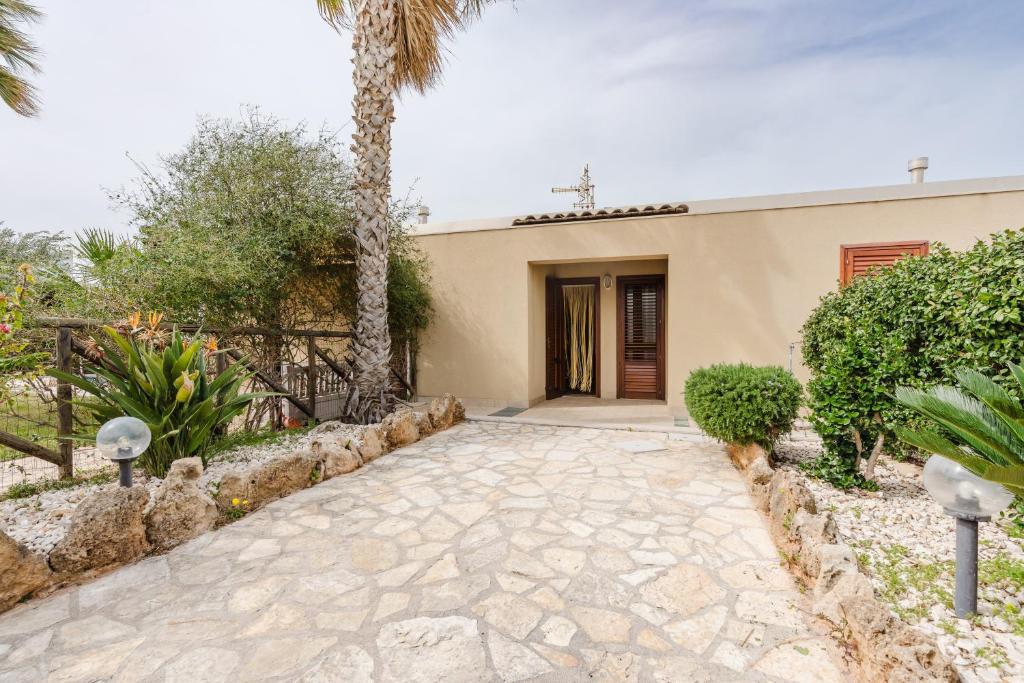 a house with a palm tree and a walkway at Villetta Marettimo Cornino in Custonaci
