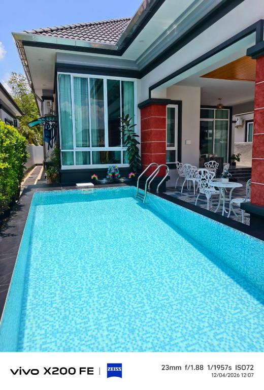 a swimming pool in front of a house at Aroyapoolvilla69 in Ban Yep Chaeng