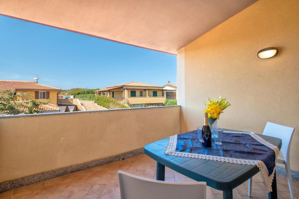 a blue table with a vase of flowers on a balcony at Baia delle mimose vista mare in Badesi