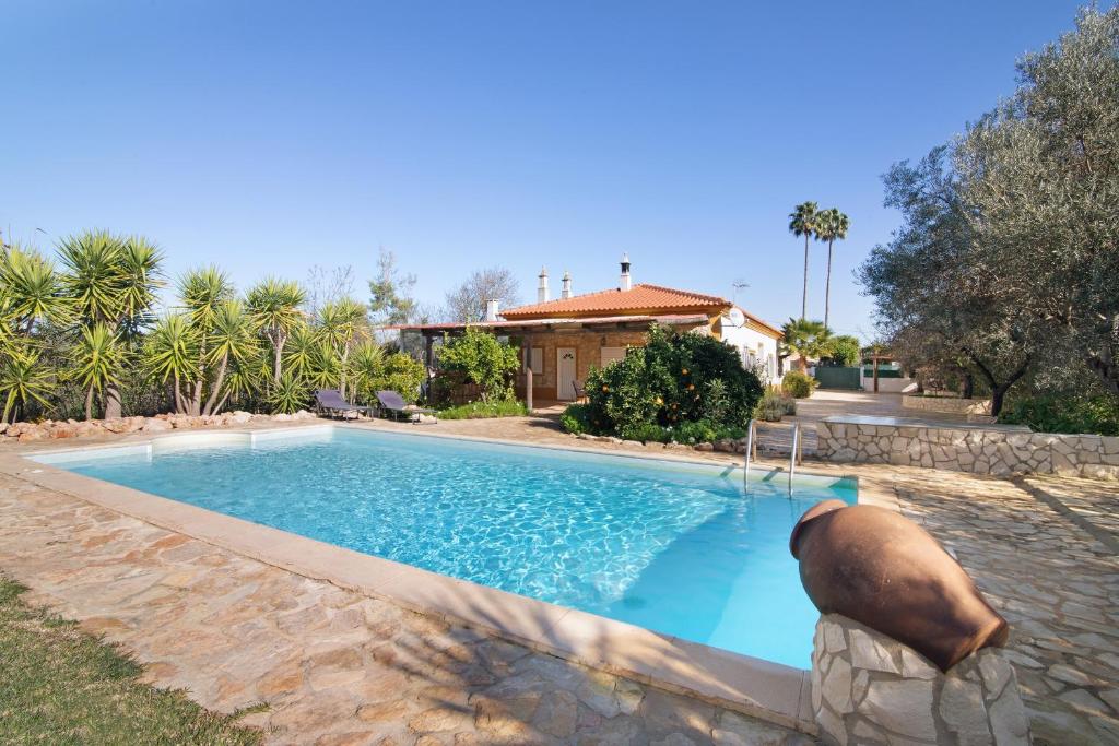 a swimming pool with a statue in front of a house at Casa Palma in Paderne