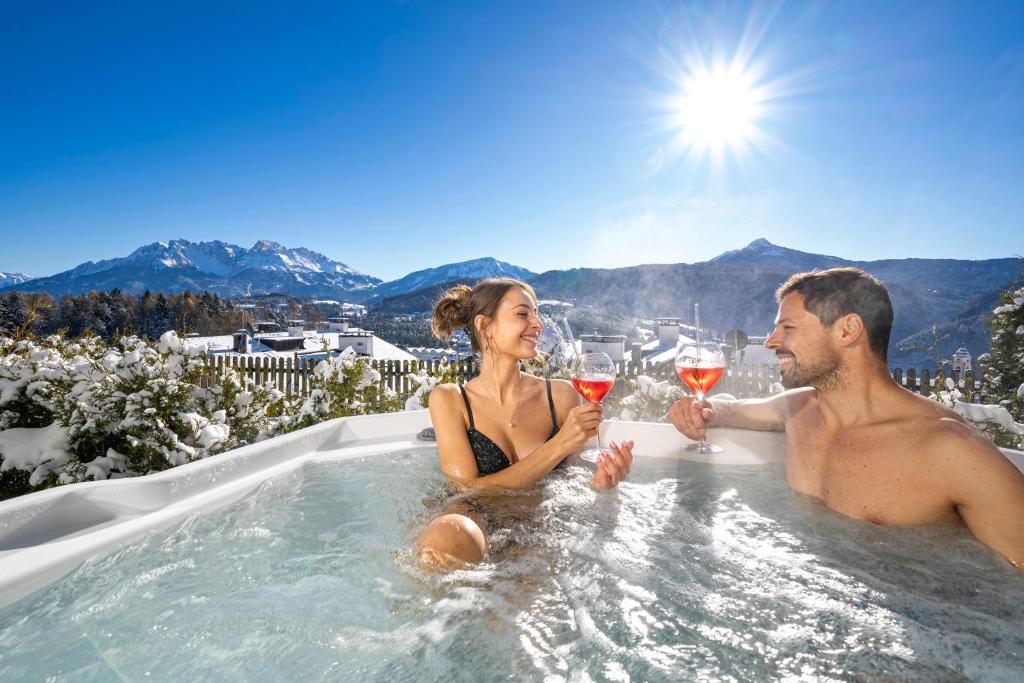 a man and woman sitting in a hot tub with wine glasses at Chalet Schlossberg Latemar in Nova Ponente
