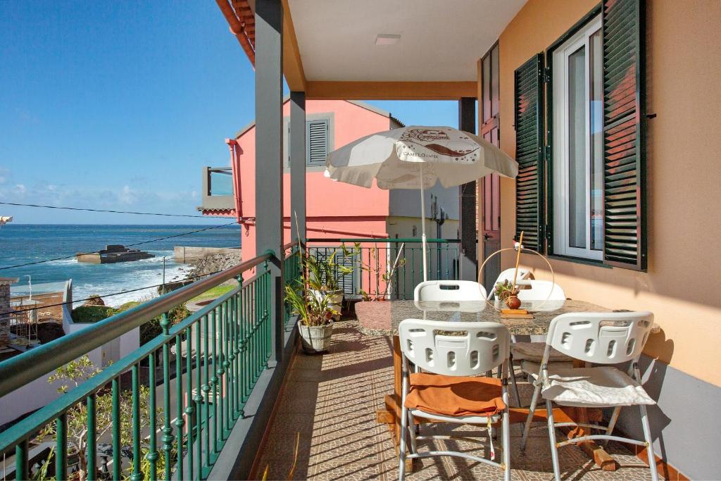 a balcony with a table and chairs and an umbrella at Casa Orquidea T3 in Ponta do Sol