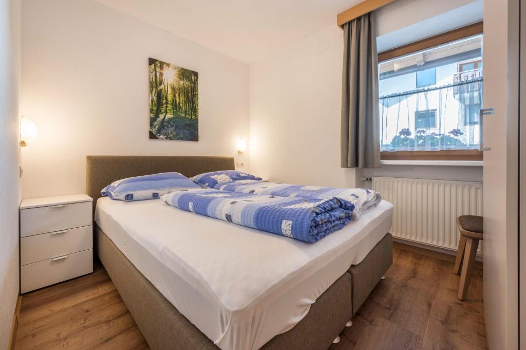 a bedroom with a large bed with blue sheets at App Sonne Nr 16 in Lutago