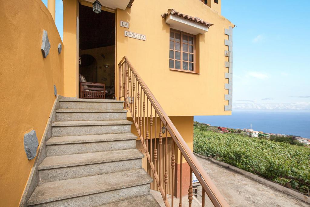a staircase leading up to a yellow building with the ocean at Tmg Casa La Chocita in Los Realejos