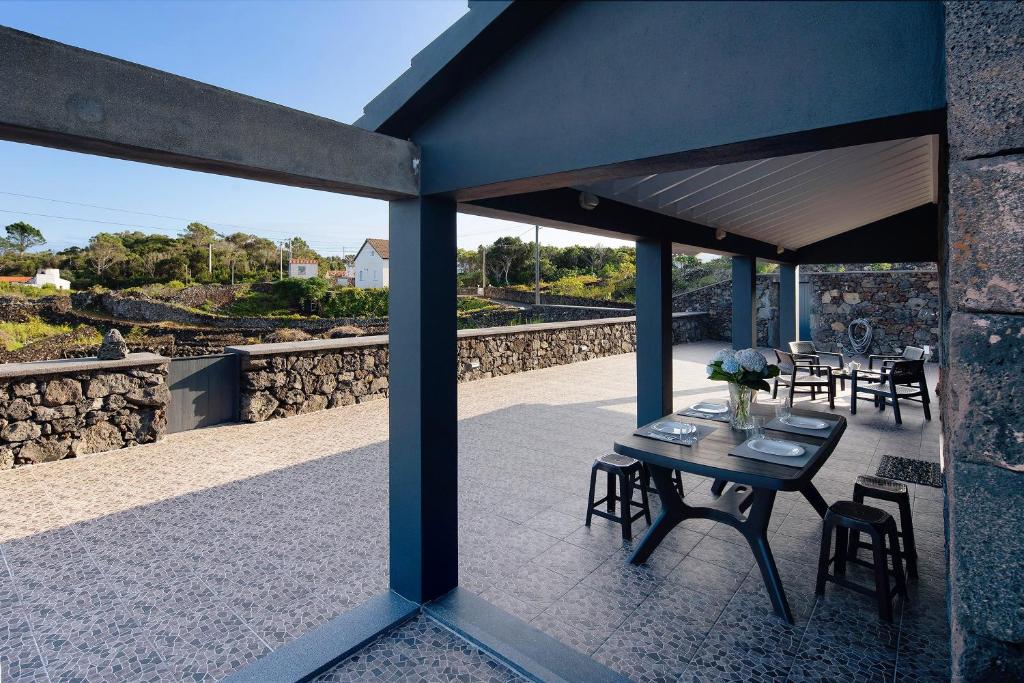 a patio with a table and chairs and a stone wall at Adega do Portinho Velho in Piedade
