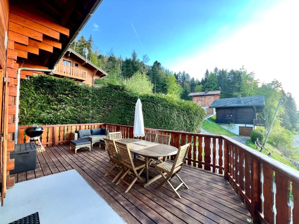 a patio with a table and chairs on a wooden deck at Chalet Mouflon - Vue lac imprenable in Thollon