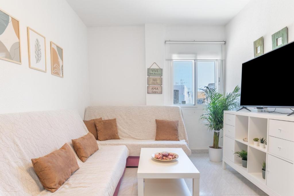 a white living room with a couch and a tv at Apartamento a pie de playa in Barbate