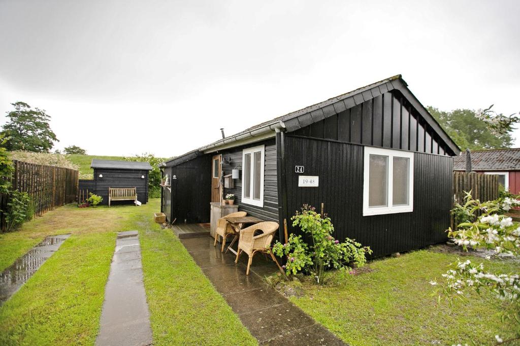 a black house with a table and chairs in a yard at Lütte Hütte in Hennstedt