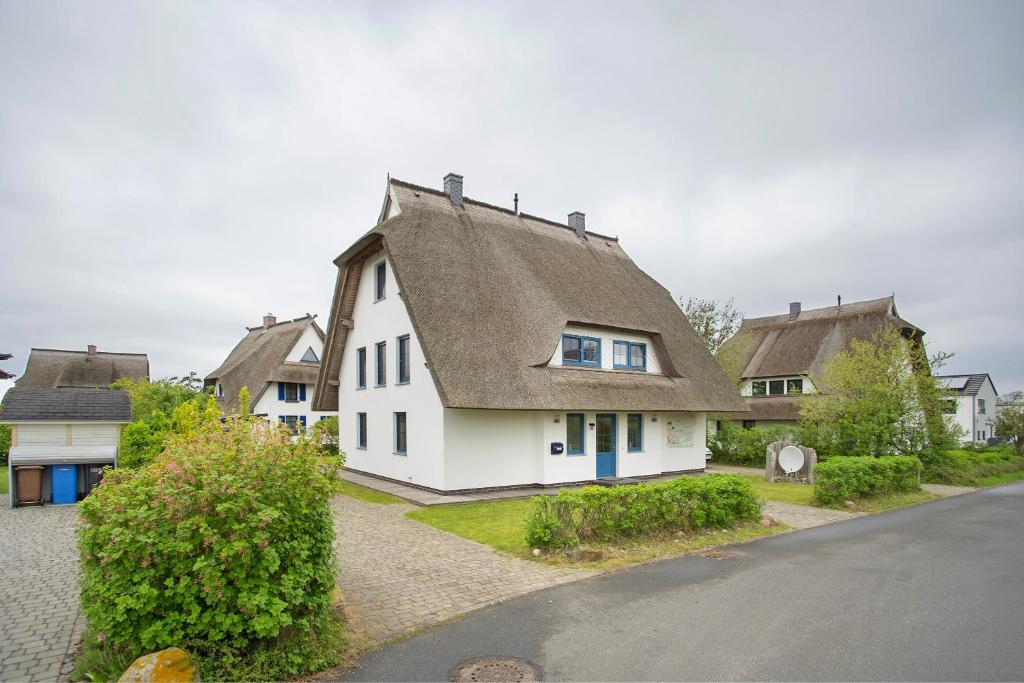 a white house with a brown roof and a street at Ferienhaus Seepferdchen in Dranske