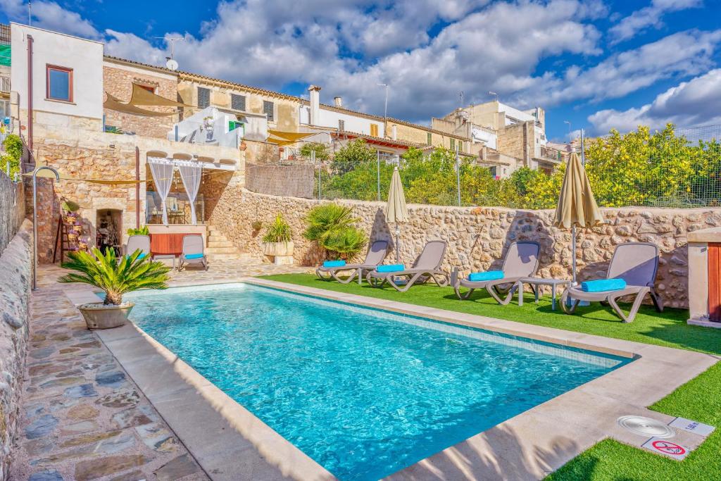 a pool with chairs and umbrellas next to a house at Casa del Sol in Búger