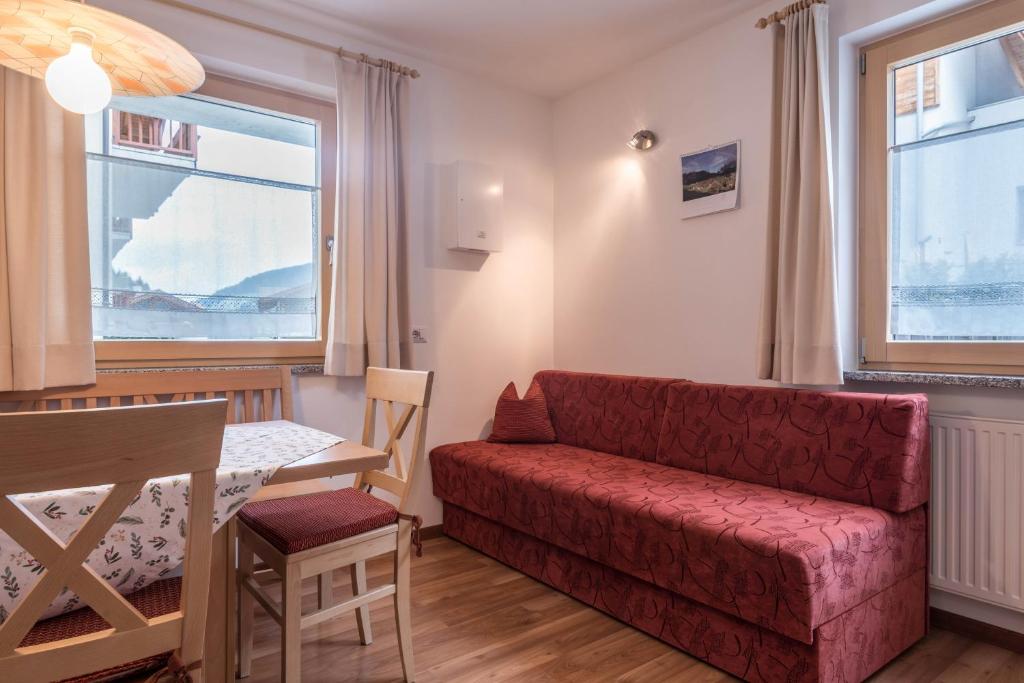 a living room with a red couch and a table at Hilber Fermeda in Villnoss