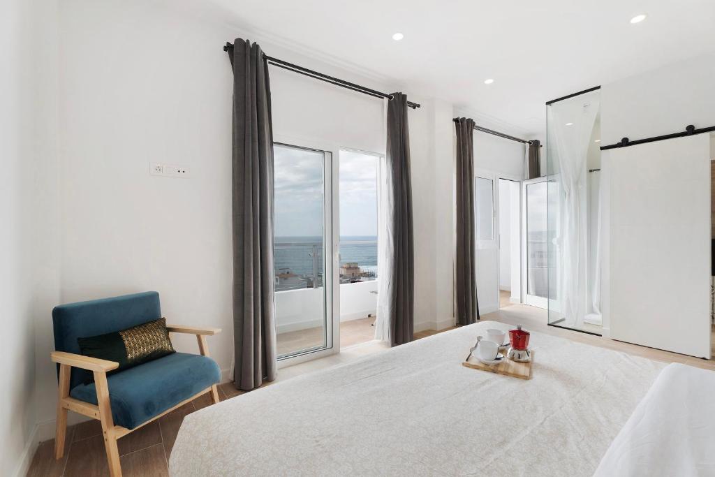 a bedroom with a blue chair and large windows at Punta del Hidalgo La Laguna in Punta del Hidalgo