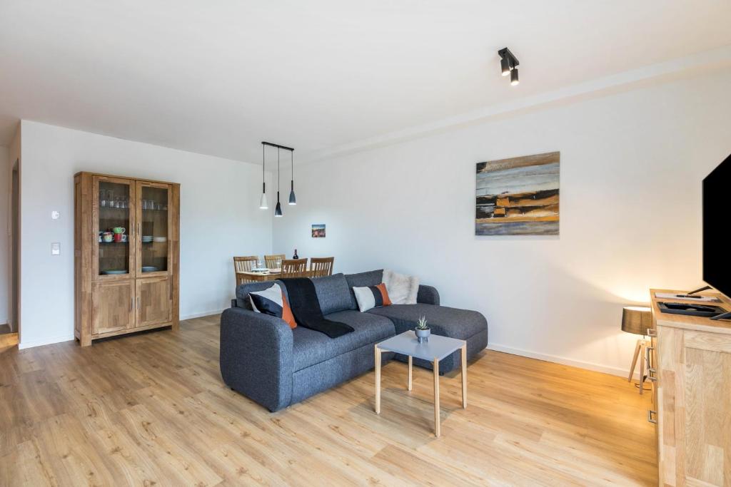 a living room with a blue couch and a table at Zum Krähenholz Wohnung 9 in Husby