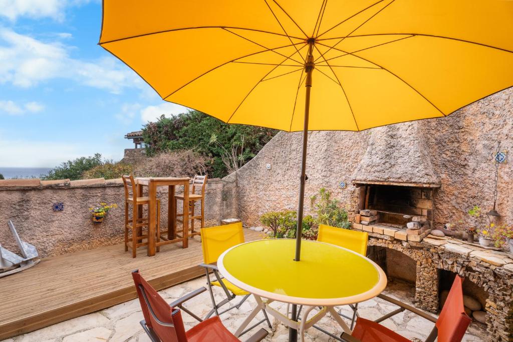 a yellow table and chairs with an umbrella on a patio at Bastidon Avec Terrasse Vue Mer in Carqueiranne