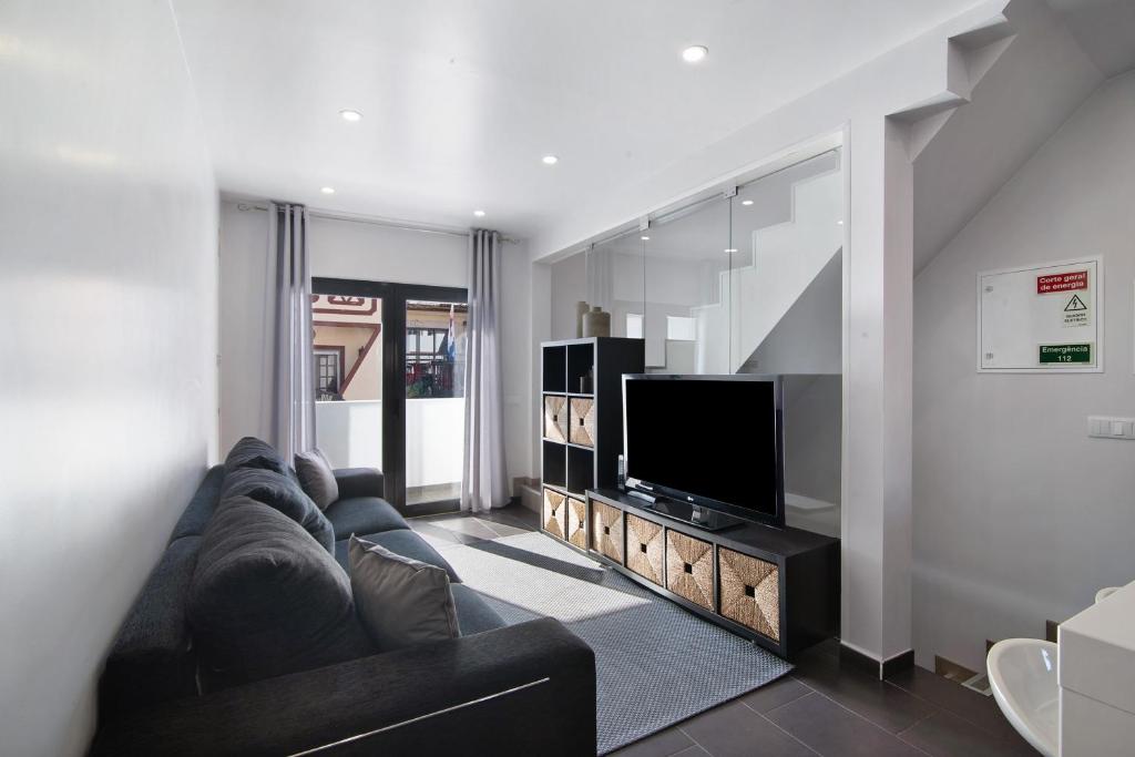 a living room with a couch and a flat screen tv at Be Glow Home in Alvor