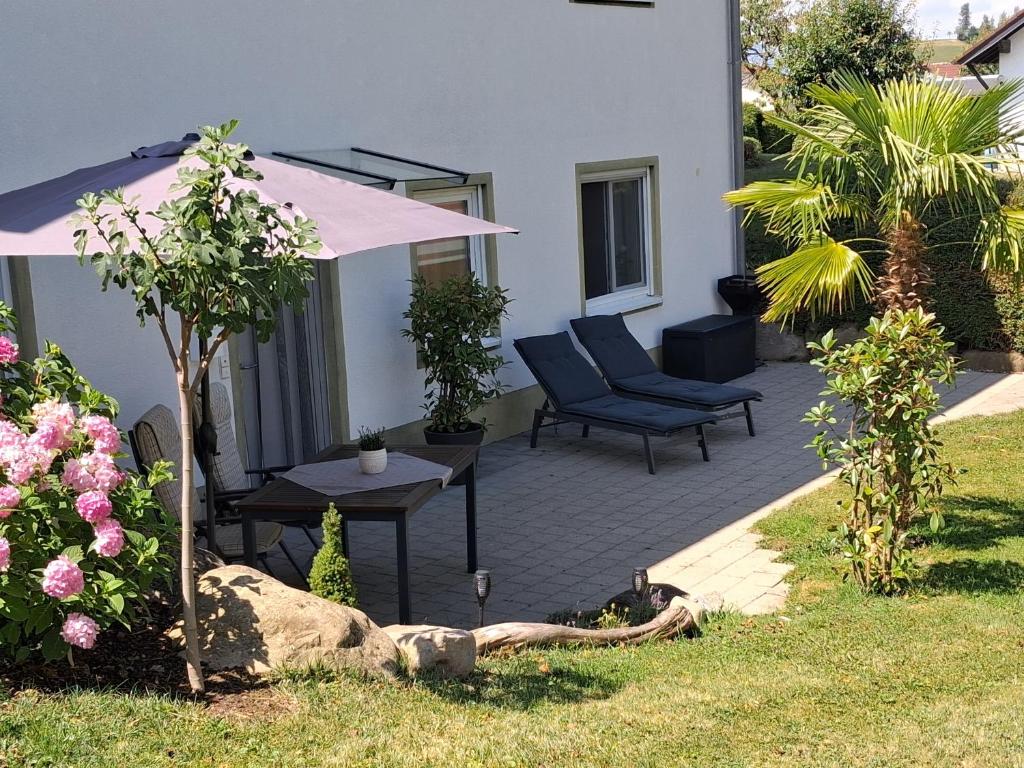 a patio with a chair and an umbrella and a table at Tobel Lounge in Sigmarszell