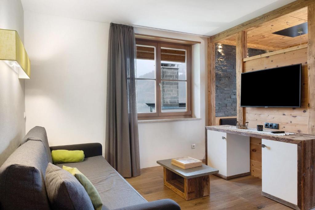a living room with a couch and a desk with a television at Angerle Alm Apt Similde B in Carezza al Lago